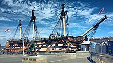 A picture of HMS Victory, the world's oldest commissioned naval ship, situated in Portsmouth's dry dock. The ship itself is missing its figurehead in this photo, but retains its original sails.