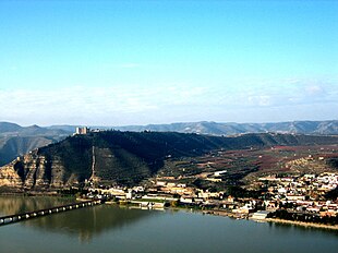 Photo of a large river, with a town on the far bank at center and right, while a large bluff rises at the left