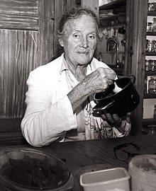 Bauermeister holding a pot in her kitchen while smiling for the camera