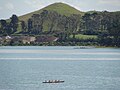 Puketutu Island's Pinnacle Hill, with a waka or canoe in the foreground.