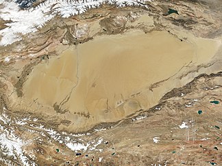 Satellitenaufnahme des Tarim-Beckens mit der Taklamakan-Wüste; im Süden davon liegen das Gebirge Kunlun Shan und die nordwestlichen Ausläufer des Tibetischen Hochlandes. (NASA/MODIS, Okt. 2001)