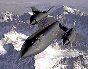Dryden's SR-71B Blackbird, NASA 831, slices across the snow-covered southern Sierra Nevada Mountains of California after being refueled by an Air Force tanker during a 1994 flight. SR-71B was the trainer version of the SR-71. Notice the dual cockpit to allow the instructor to fly.