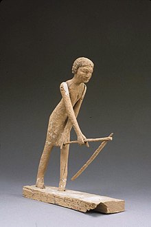Wooden model of men bent over with a hoe.