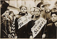 Two girls wearing banners bearing the slogan "ABOLISH CH[ILD] SLAVERY!!" in English and Yiddish, 1909