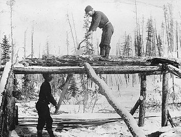 Two men sawing lumber with a pitsaw, the log on trestles rather than over a saw pit