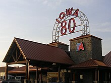 A large building with a high-peaked roofline. A large neon sign reads "Iowa 80".