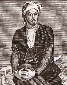 Nasimi sitting with his hands wrapped around his knee with a city in the background