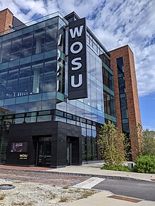 A four-story brick and glass building, freshly constructed, with vertical W O S U signage sticking out