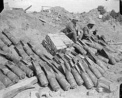 A picture taken in 1918 showing two men of the 9th Battalion, Royal Sussex Regiment sit beside a dump of 6-inch Mortar bombs.