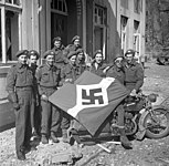 Canadian soldiers in Friesoythe with a captured Hitler Youth flag