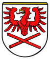 Gemeinde Hausham In Silber über zwei schräg gekreuzten roten Stäben schwebend ein halber roter Adler mit goldenem Schnabel.