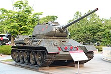 A large tank, heavily armed and armored outside a modern museum