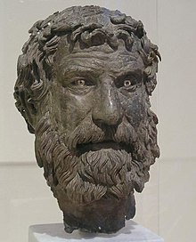 Bronze head of bearded man with furrowed brow and unruly hair