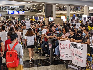 Protesters handing leaflets and showing signs to tourists arriving in Hong Kong