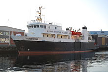 Photograph of a modern motor ship with a black hull and white superstructure