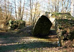View of the ruined arch of a bridge isolated in a meadow