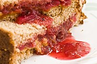 Close-up view of a cut peanut butter and jelly sandwich showing soggy whole wheat bread