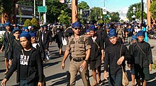 Young men in blue headgear walking down a city street