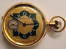 Gold-toned vintage Wilsdorf & Davis hunter-case pocket watch, golden dial with foliage and green enamel, and Wilsdorf & Davis logo on the dial.