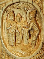 Ivory tusk depicting a man with head dress and bare feet showing the direction to the Buddha, and a second monk looking similar to the Buddha.