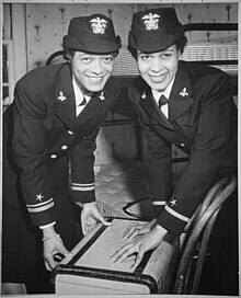 Two African-American WAVE officers in dress uniforms shutting a suitcase