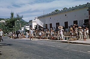 A queue of people with water containers outside a building