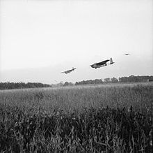 Large gliders in the sky, preparing to land in a field