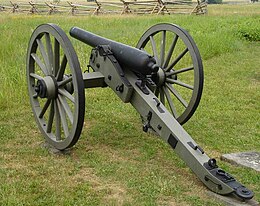 Photo shows a black cannon mounted on a wheeled carriage. It points away from the viewer.