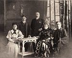 Old photo of five Pontic Greeks in western dress, seated or standing inside.