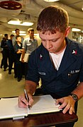 Aboard USS Ronald Reagan, June 7, 2004: Navy sailor writes a personal message in book to be presented to Nancy Reagan during President Ronald Reagan's interment ceremony.