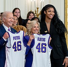 Reese posing with Joe Biden and Jill Biden, who are both holding LSU jerseys, during her team's White House visit in 2023