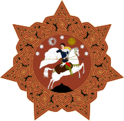 A round orange badge with six points and a horse-mounted man in the centre