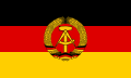 The flag of East Germany, a charged horizontal triband.