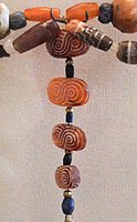 Four oval-shaped carnelian beads with guilloché pattern and one cylindrical bead with stepped pattern (top right) found in Susa excavations, Akkadian Empire or Ur III period. The carnelian is most probably from the Indus region, but the designs are typically Near-Eastern.[41][30]