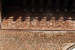 Arabic calligraphic inscription carved into wood in the early 14th-century Sahrij Madrasa in Fes, surrounded by other arabesque decoration