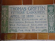 A tablet formed of two large tiles, bordered by green flowers in the style of the Arts and Crafts movement