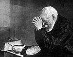 Grace, a black and white photo of a bearded man bowed in prayer