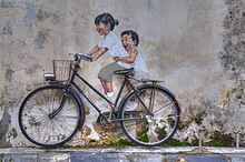 A mural depicting two children riding a bicycle.
