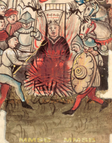 A man wearing a hat depicting two demonic figures is being burned. He is surrounded by armed people.