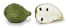 soursop fruit, whole and in section. It is green with scales has white flesh and black seeds