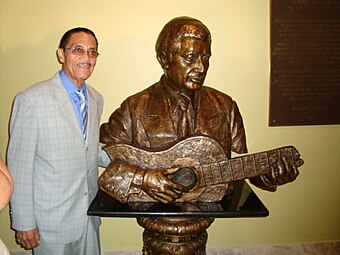 Puerto Rican singer Tommy Figueroa posing with his bust in the Center for Fine Arts in Juana Díaz