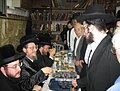 L to R: Grand Rabbi Shlomo Yosef Englard of Radzin at a Tisch in the Central Radzin Institutions in Bnei Brak. To the right is Rabbi Yitzchok Englard of Radzin-Bnei Brak, to the left is Rabbi Nosson Nochum Englard of Radzin-Yerushalayim