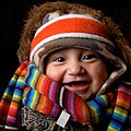 A baby wearing many items of soft winter clothing: headband, cap, fur-lined coat, scarf and sweater, expressing comfort of clothing