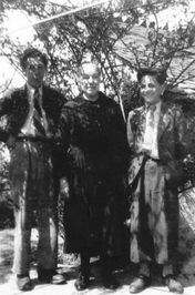 black and white photograph of two boys standing on either side of an older woman under a tree