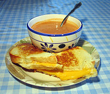 A bowl of soup and a cut sandwich on a plate