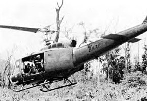 Military helicopter with main door open, over jungle
