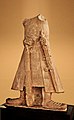 Statue of Kushan emperor Kanishka I (c. 127–150 CE) in long coat and boots, holding a mace and a sword, from the Māt sanctuary in Mathura. An inscription runs along the bottom of the coat: Mahārāja Rājadhirāja Devaputra Kāṇiṣka "The Great King, King of Kings, Son of God, Kanishka"