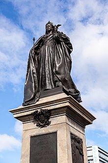 A bronze statue of a crowned Queen Victoria, holding a scepter and orb, atop a stone pedestal