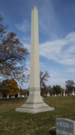 The Butler family plot in St. Paul, Minnesota is marked by a large stone obelisk bearing only the name "BUTLER"; Pierce's stone and gravesite are in the foreground, obscured by tall grass.