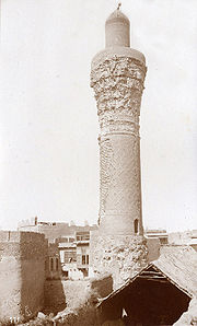 Sepia-toned black-and-white photograph of a much-weathered minaret